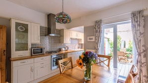Una cucina con mobili bianchi, un forno a microonde, un fornello e una vetrina decorativa.