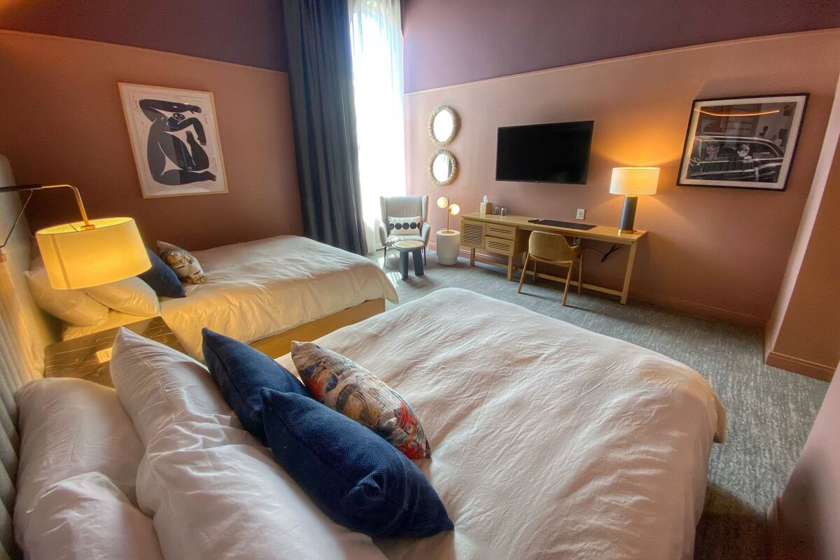 Une chambre d’hôtel avec deux lits, un bureau, une télévision et une chaise.