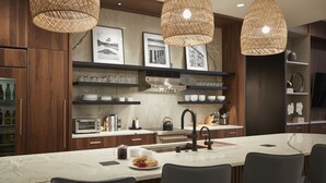 Una cocina moderna con una isla de mármol, armarios de madera oscura y lámparas colgantes de mimbre.