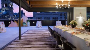 Un área de comedor al aire libre con vistas a arquitectura histórica, techo de madera y una mesa preparada para una comida.