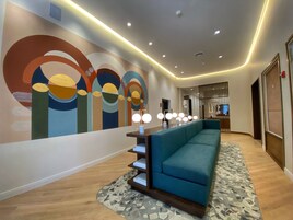 A modern lobby with a teal sofa, a patterned rug, and a wall with abstract art.