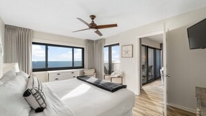 A modern hotel room with a large bed, a ceiling fan, a TV, and a balcony with a view of the sea. - Emerald Towers 902 (Destin)