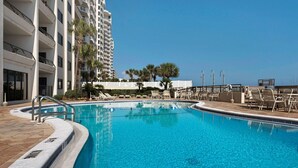 A swimming pool with clear blue water, surrounded by lounge chairs and a building with balconies. - Emerald Towers 902 (Destin)