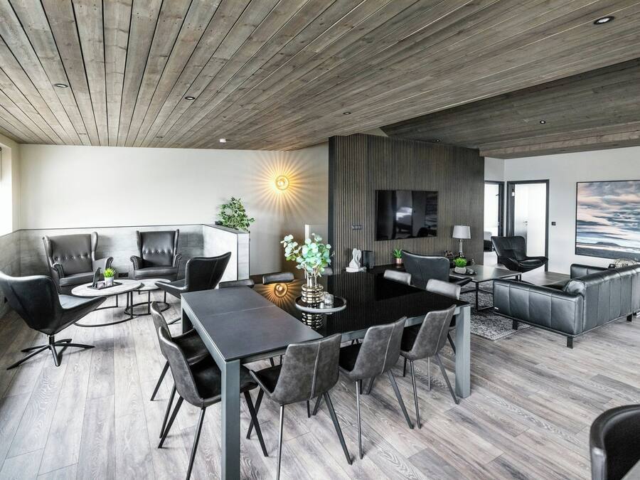 Una sala de estar moderna con comedor, muebles de cuero, televisor y un ventanal con vistas.