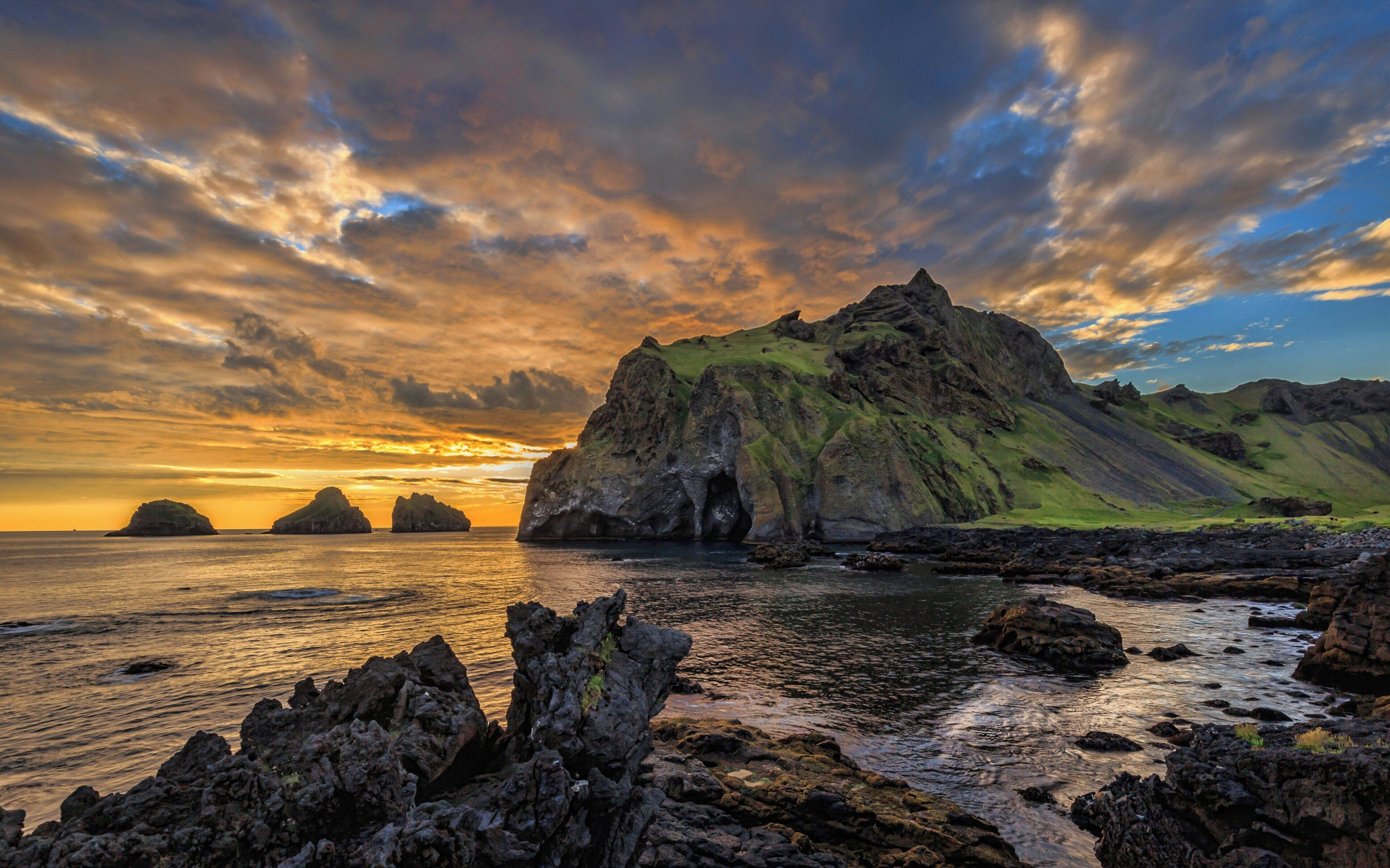 A rugged coastline with rocky outcrops and a prominent mountain peak.