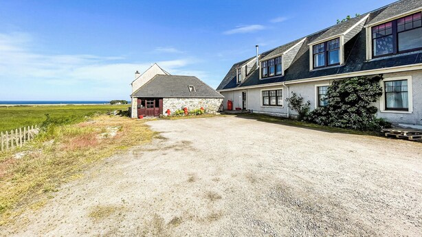 A two-story house with a gravel driveway and a view of the sea. - Fourpenny Studio - UK34745 (Skelbo, near Dornoch)