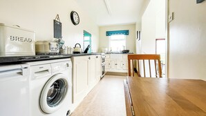 A compact kitchen with a washing machine, a bread maker, and a stove. - Fourpenny Studio - UK34745 (Skelbo, near Dornoch)
