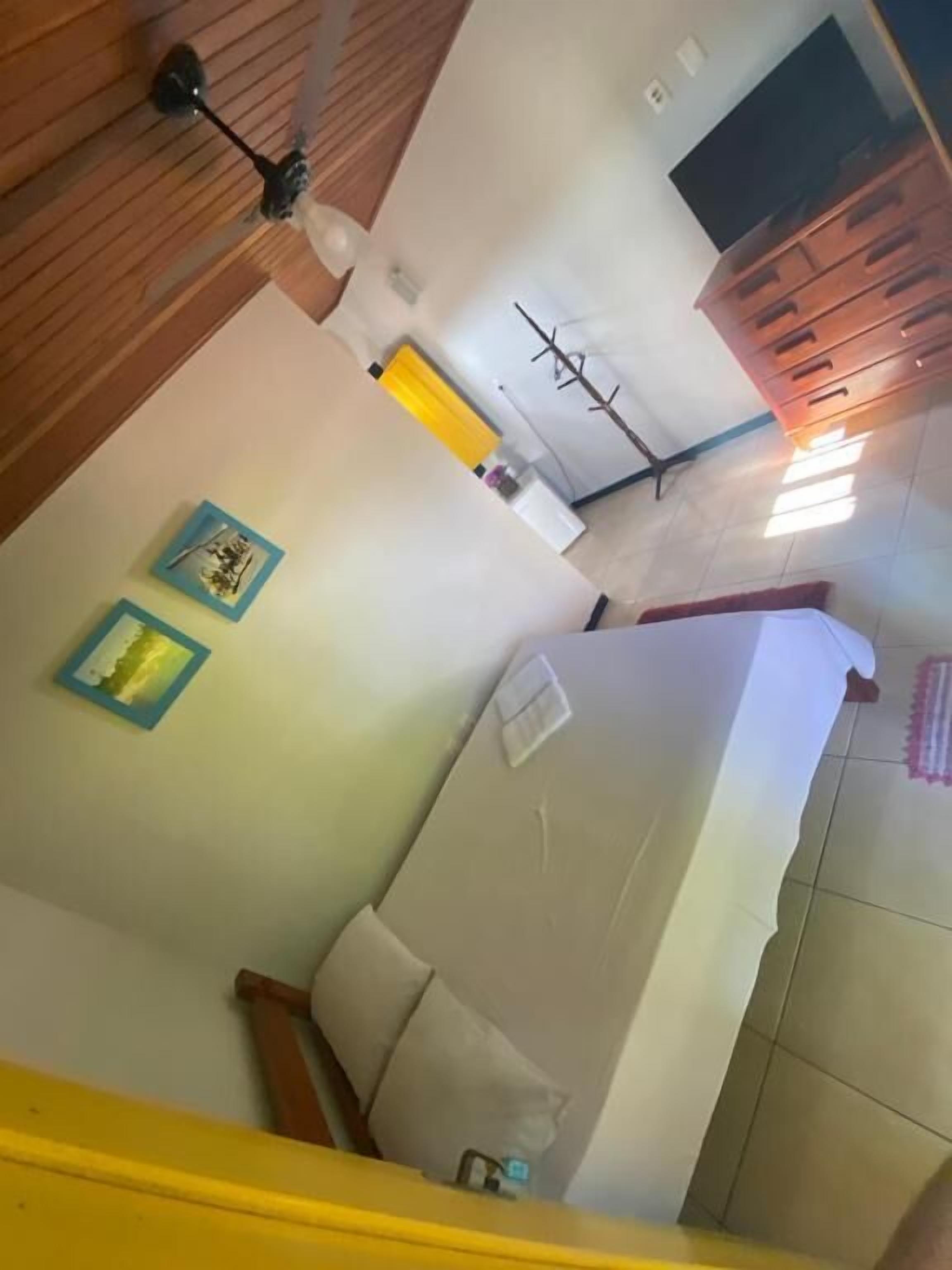 A room with a bed, a wooden ceiling, a white wall, and a wooden dresser.