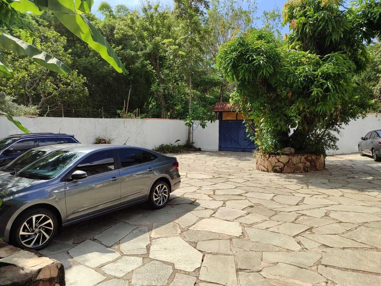 A paved courtyard with a parked car, a stone wall, and a blue door.