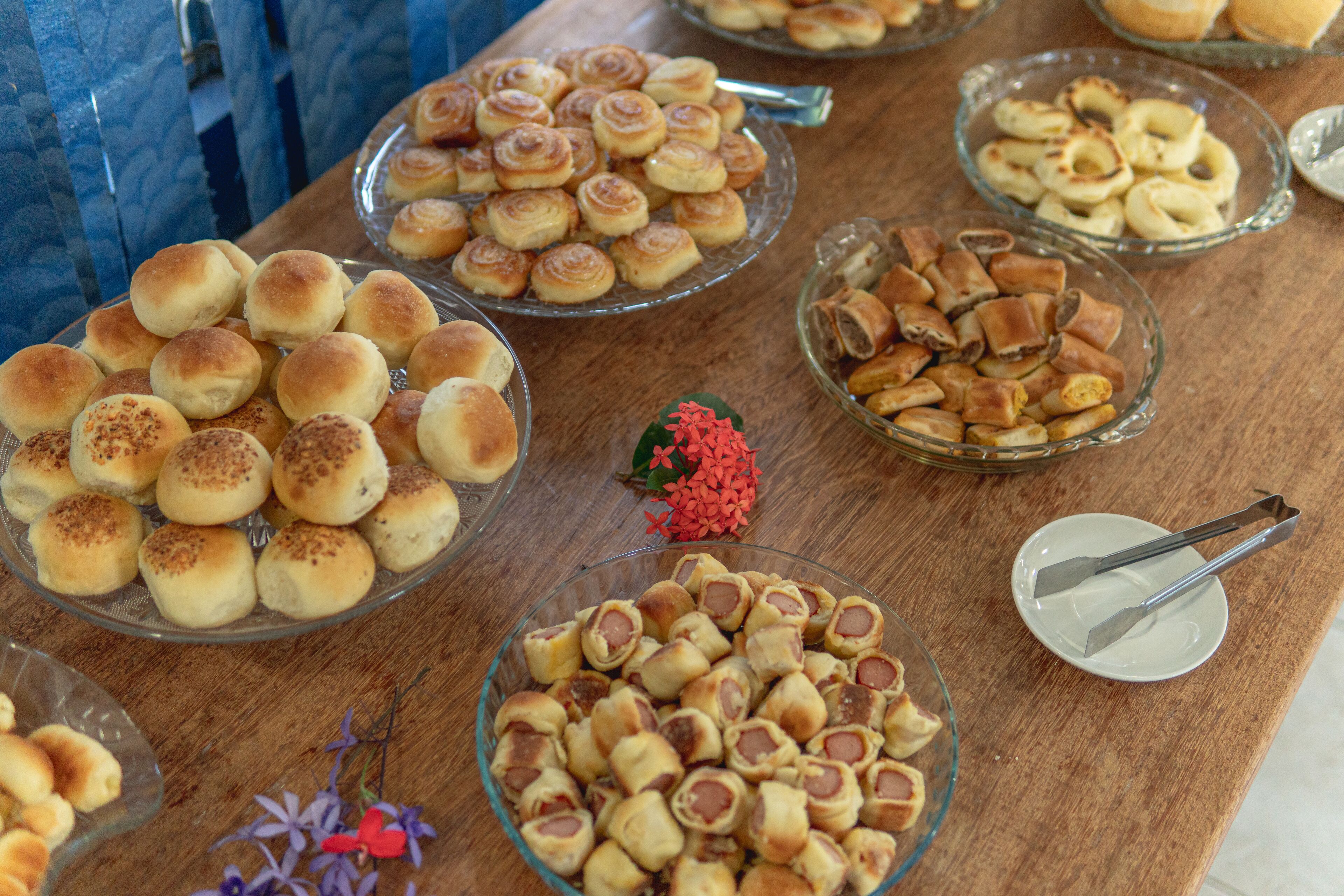 A buffet table with various baked goods including rolls, pastries, and bread rolls.