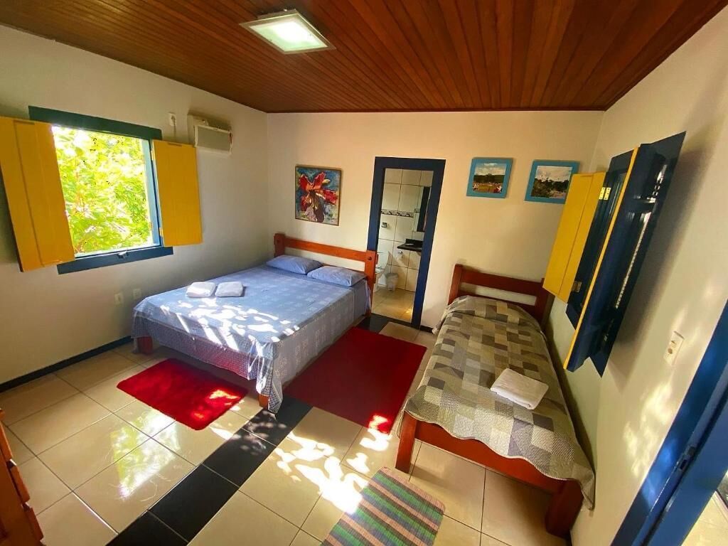 Un dormitorio con dos camas, una ventana con persianas amarillas, un espejo y una puerta.