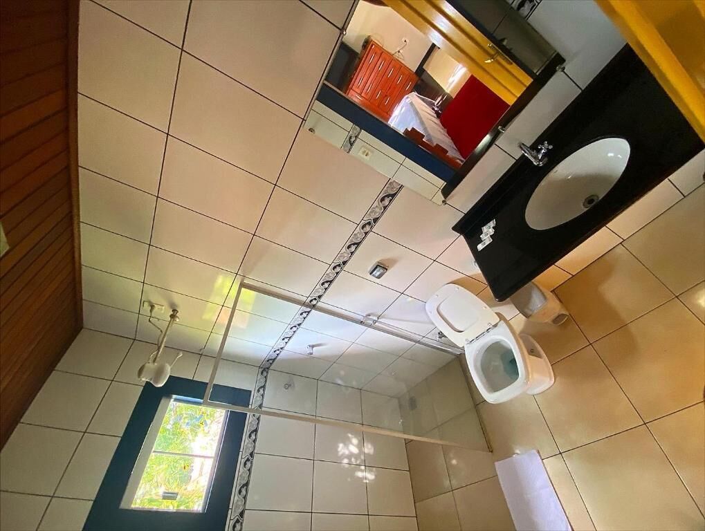 A bathroom with a toilet, sink, and window.