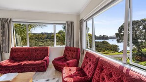 A room with two red velvet sofas facing a large window overlooking a scenic landscape.