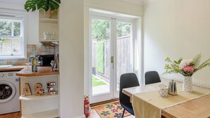 Una cocina con lavadora, una zona de comedor con mesa y sillas, y un ventanal con vistas al exterior.