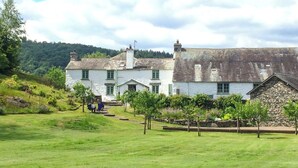 A traditional stone house with a grassy yard and a small garden area. - 3 bedroom accommodation in Bowness on Windermere (Bowness on Windermere)