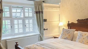 A bedroom with a bed, a nightstand, a lamp, and a window with curtains. - 3 bedroom accommodation in Bowness on Windermere (Bowness on Windermere)