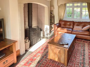 A cozy living room with a leather sofa, a wooden coffee table, and a patterned rug.
