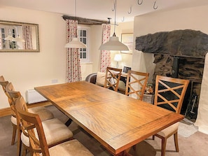 Une salle à manger avec une table en bois, des chaises, une cheminée et un miroir.