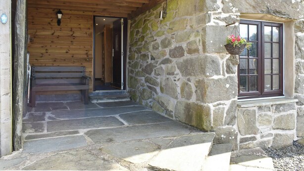 A stone building with a wooden porch and a stone staircase leading to a door.