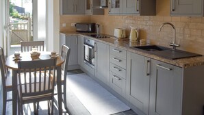 A modern kitchen with grey cabinets, a built-in oven, a microwave, and a sink.