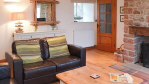 Una sala de estar acogedora con un sofá de cuero, una mesa de centro de madera y una chimenea.
