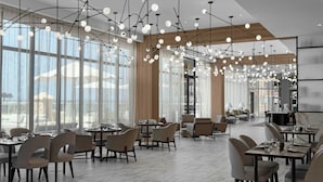 Un comedor amplio con candelabros modernos, ventanas grandes y una variedad de opciones de asientos.
