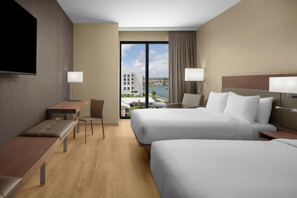 Una habitación de hotel con dos camas, un escritorio, una silla y un televisor.