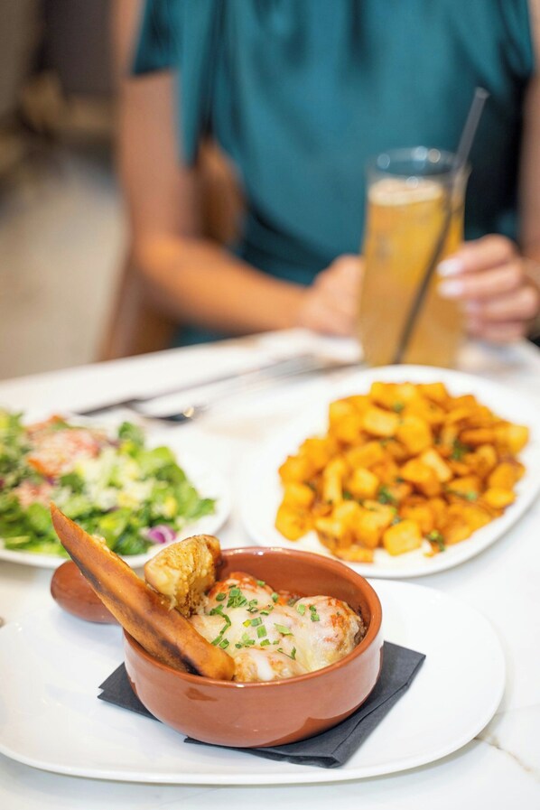 Una mesa de comedor con varios platos, incluyendo un tazón de sopa, una porción de papas fritas y una ensalada.