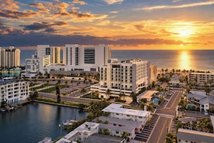 A coastal hotel complex with multiple buildings, a marina, and a sunset view.