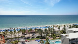 Vista de una playa con piscina y un edificio con balcones.