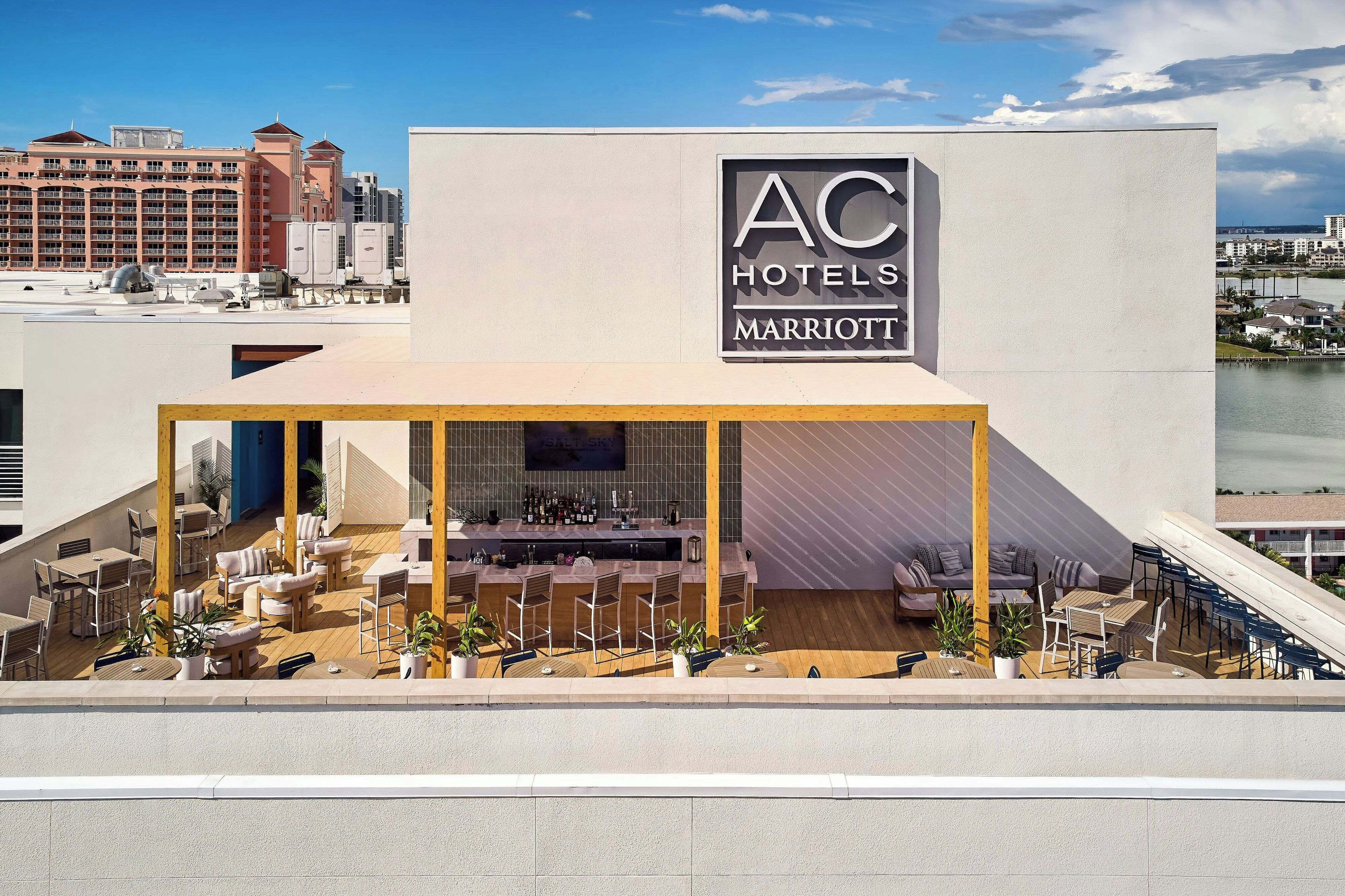 A hotel with a rooftop bar, outdoor seating, and a view of the city skyline.