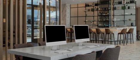 A modern bar area with two large monitors, bar stools, and a wine display.