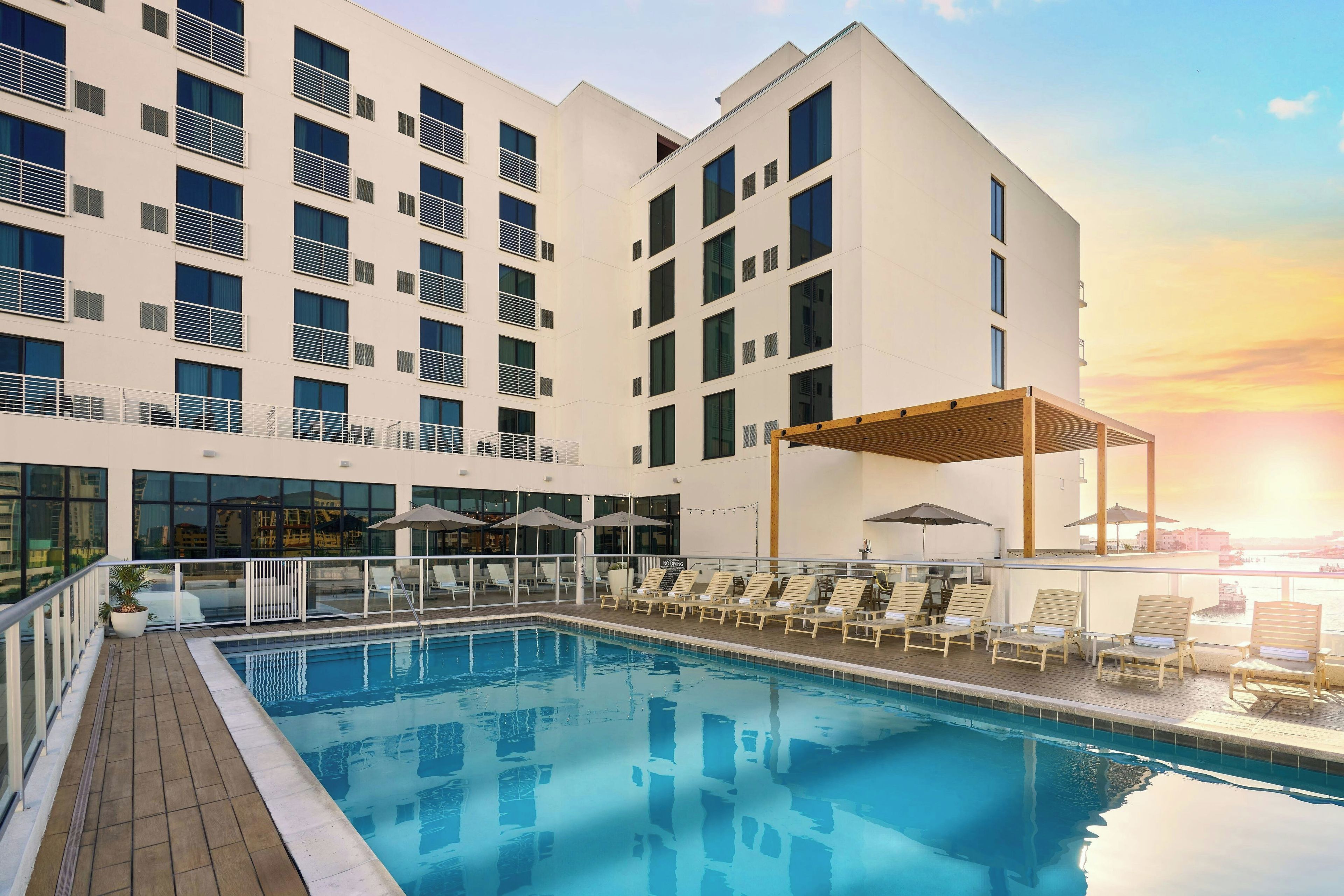 Een modern hotel met een zwembad, terras en uitzicht op de zonsondergang.