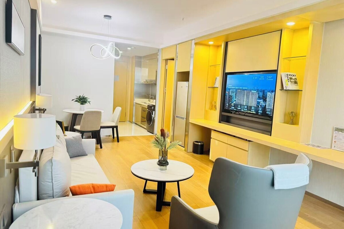 Un salon moderne comprenant un canapé, des fauteuils, une table à manger, un téléviseur et un coin cuisine.