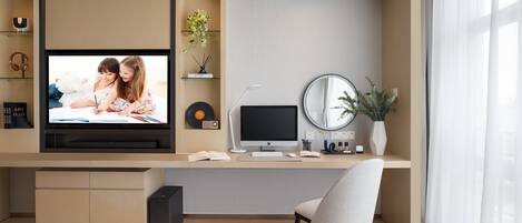 A modern home office with a TV, computer, and desk lamp.