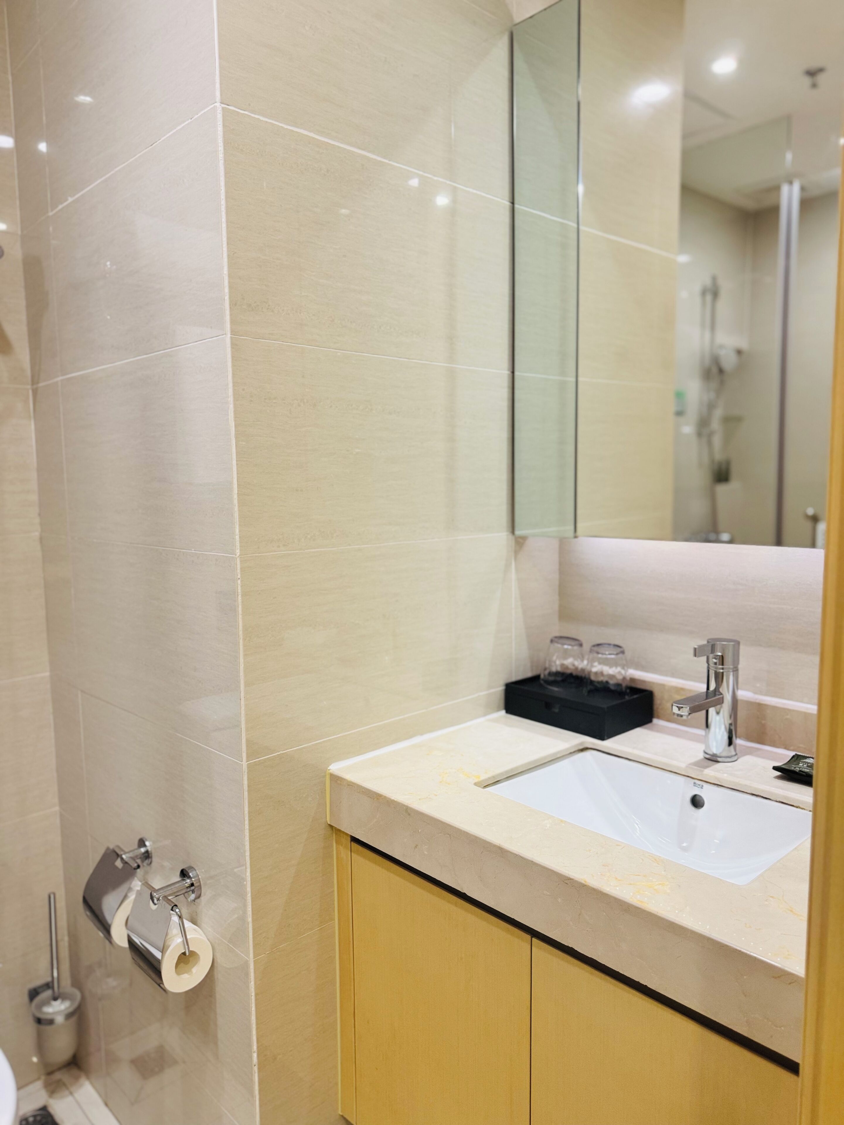 A modern bathroom with a white sink, a mirror, and a shower area.