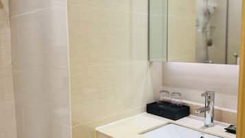 A modern bathroom with a white sink, a mirror, and a shower area.