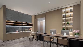 A modern office space with a long desk, multiple chairs, a marble accent wall, and a bookshelf with books and decorative items.