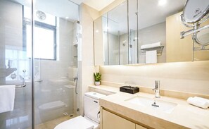 A modern bathroom with a glass shower enclosure, a white toilet, a sink with a mirror, and a small potted plant on the vanity. - Somerset Haizhu Centre Guangzhou (Guangzhou)