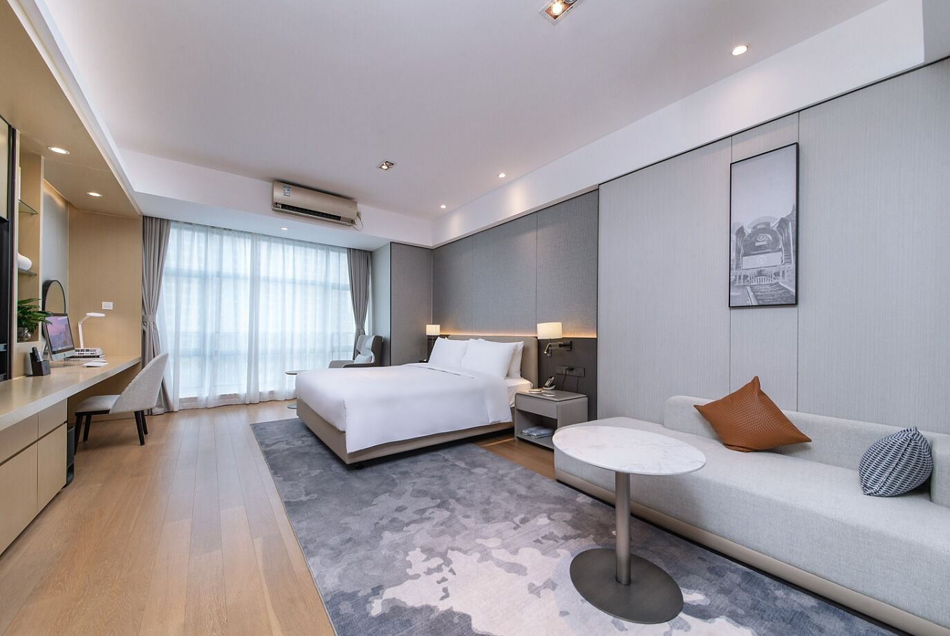 Une chambre d’hôtel moderne avec un grand lit, un canapé, un bureau et une petite table.