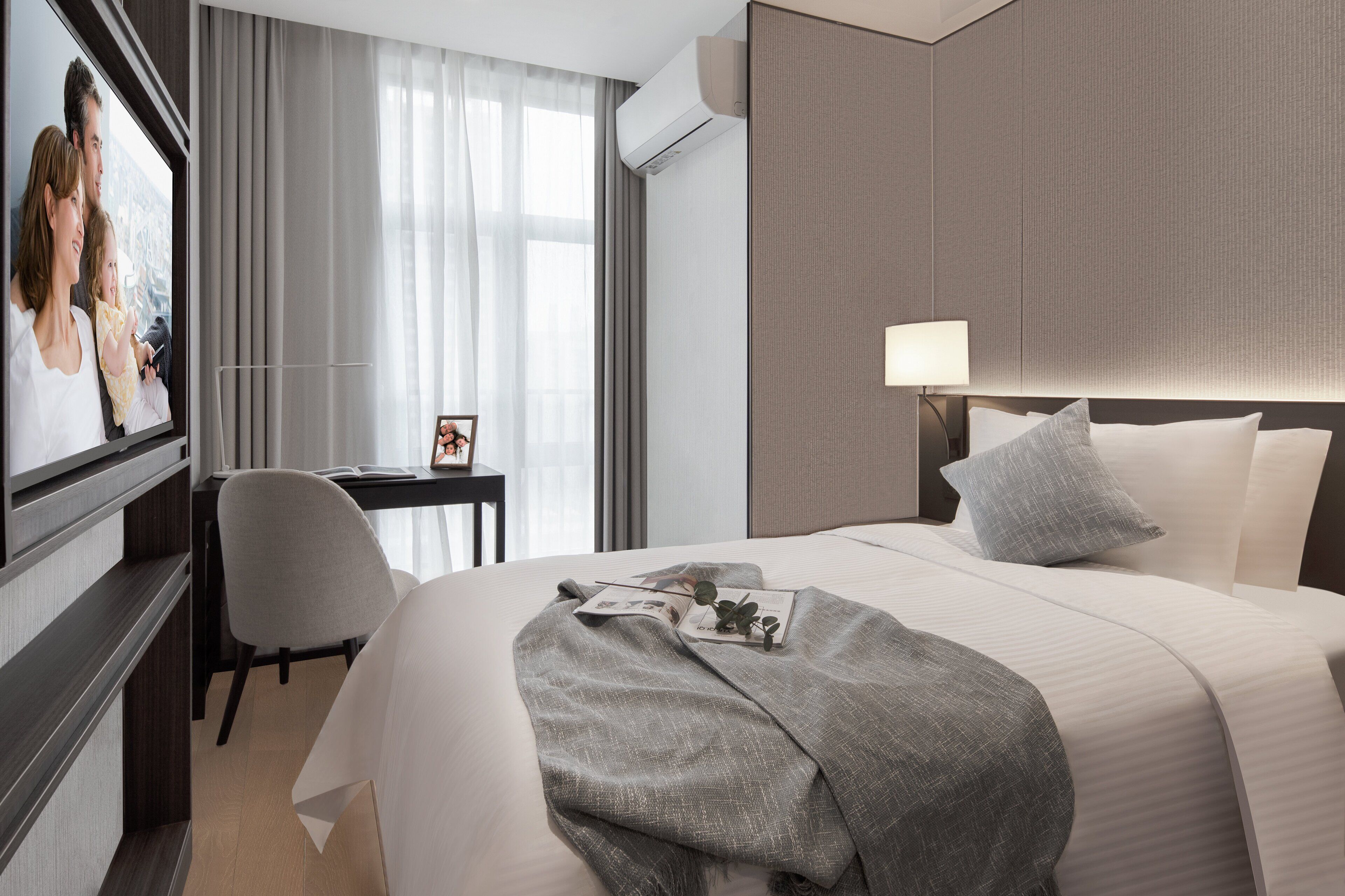 A hotel room with a bed, a desk, a chair, a TV, and a window with curtains.