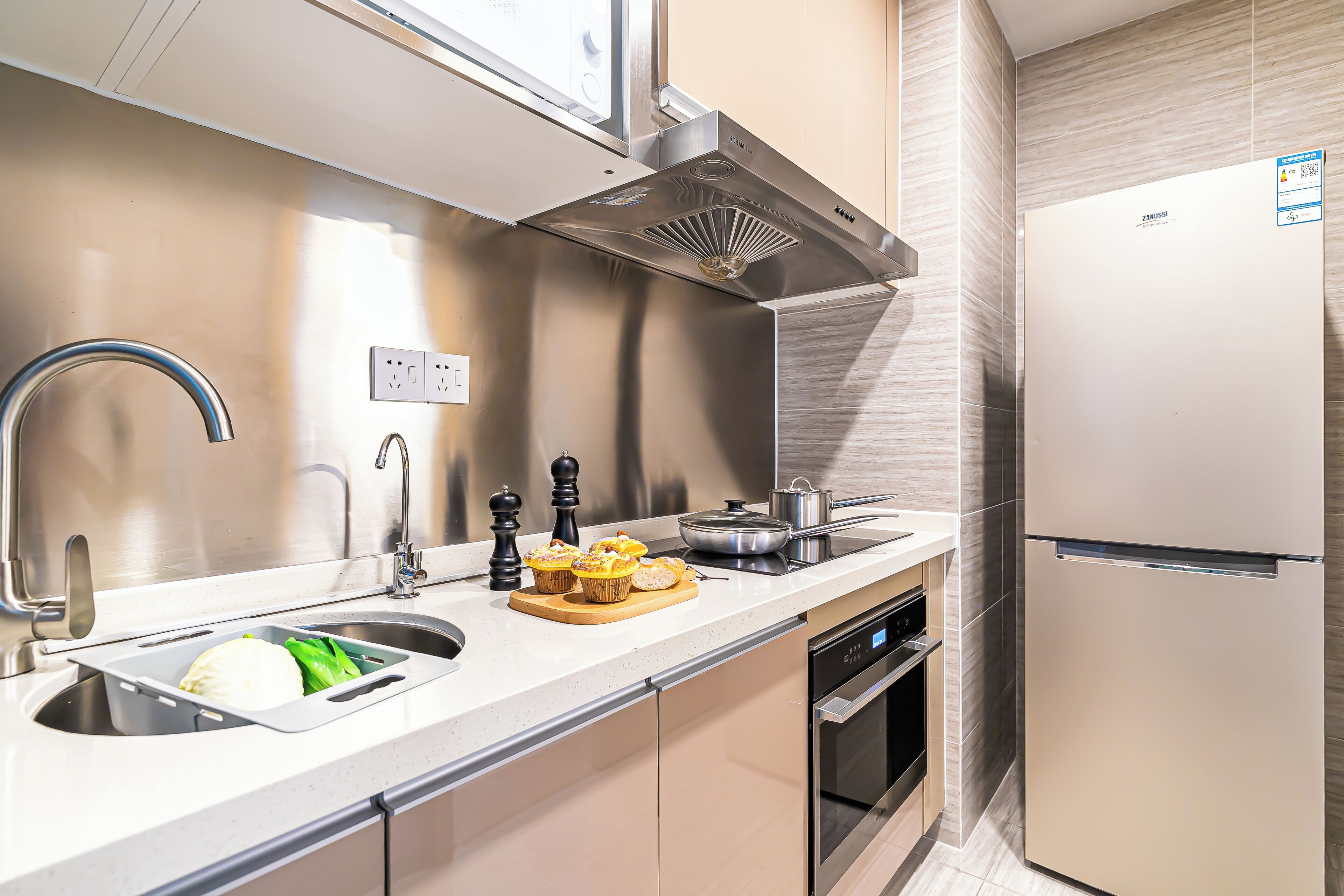 A modern kitchen with stainless steel appliances, a built-in oven, and a sink.