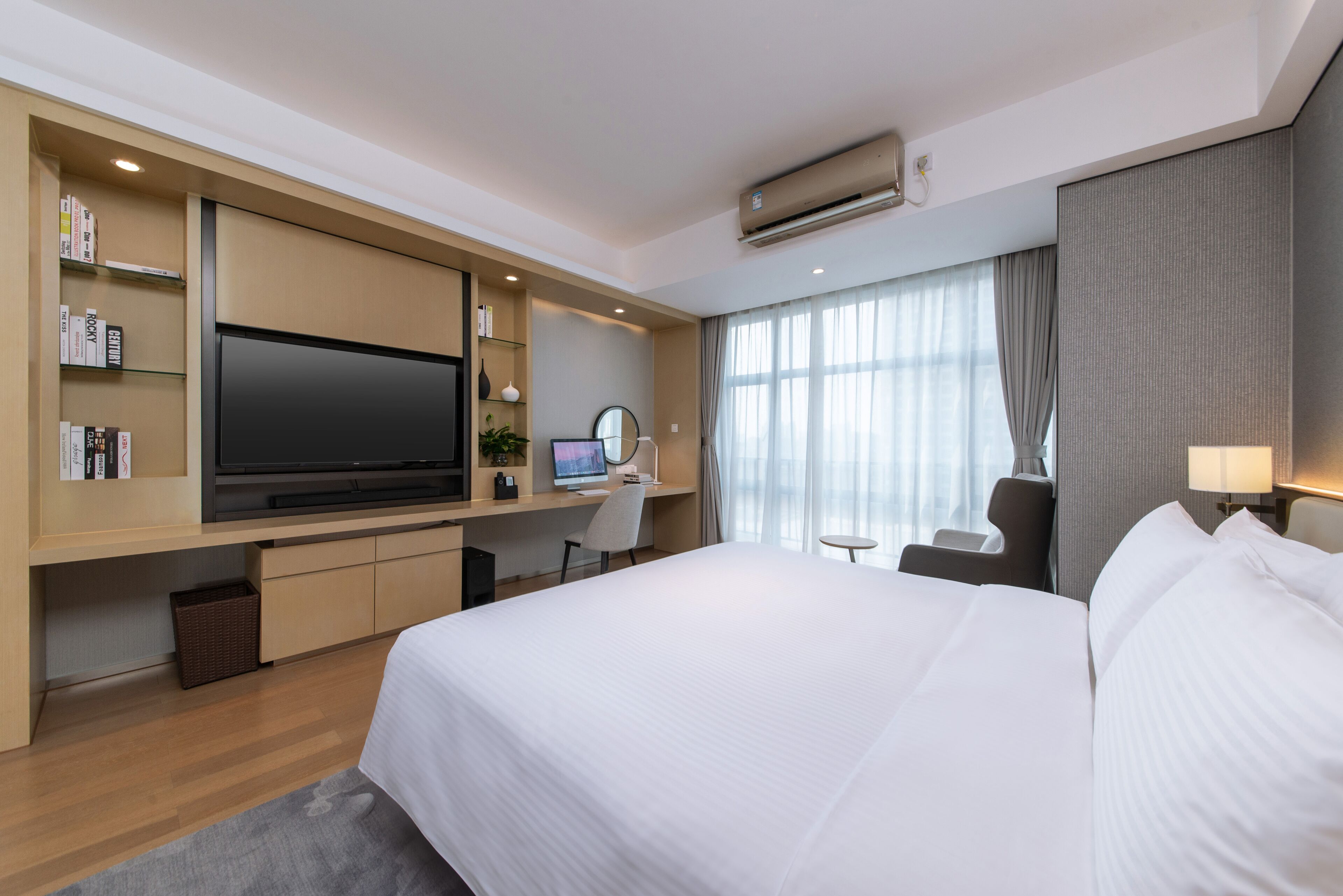 Une chambre d’hôtel avec un grand lit, un bureau équipé d’un ordinateur, un téléviseur à écran plat et une bibliothèque.