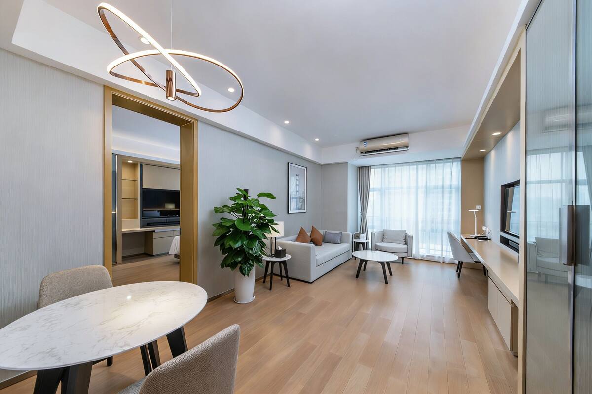 Una sala de estar moderna con una mesa de comedor, sofá y una planta grande en maceta.