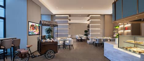 Una hall d'albergo moderna con un'area salotto, un espositore di cibo e un carrello per biciclette.