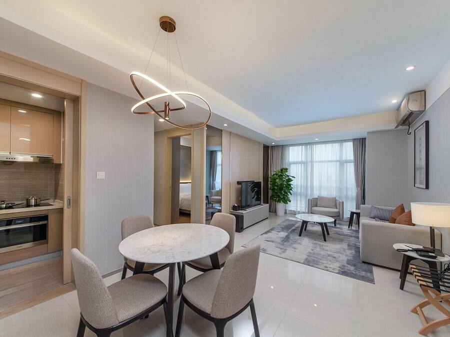 A modern hotel room with a kitchen, dining area, and living room.