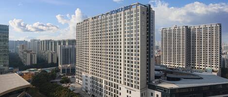 A high-rise hotel with a grid-like facade, multiple balconies, and a prominent sign at the top.