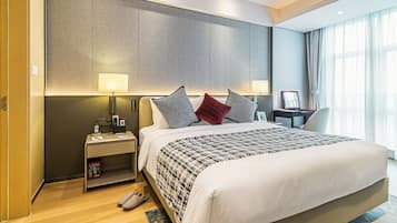 A hotel room with a large bed, bedside tables, a desk, and a view of the outdoors.