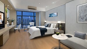 Habitación de hotel moderna con una cama grande, un sofá, un escritorio y vistas a la ciudad.