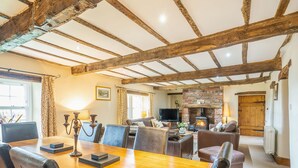 A spacious dining area with a wooden table and chairs, a fireplace, and a television in the background. - Dudmire (Appleby-in-Westmorland)